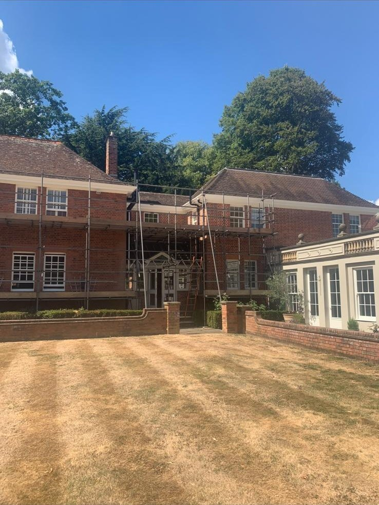 Scaffolded red-brick country house exterior during decoration works